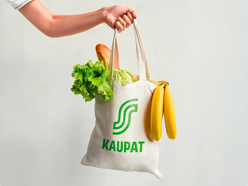 Kuva kädestä joka pitää S-Kaupat kangaskassia täynnä ruokaa.