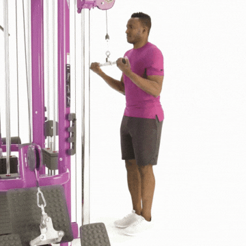 Man in workout clothes performing triceps pushdown exercise using cable tower machine