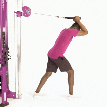 Man in workout clothes performing triceps extension exercise using cable tower machine