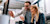 A man and a woman in business attire look at a computer screen and smile.