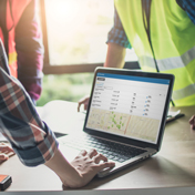 People standing around desk in reflective vests looking at Trimble Unity Maintain software.
