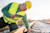 A worker in a yellow hard hat and vest inspects a train track while holding a tablet.