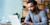 A smiling man dressed in business casual clothes looks at his laptop.