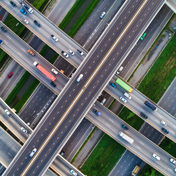 An aerial view captures a complex interchange of multi-lane highways with cars and trucks.