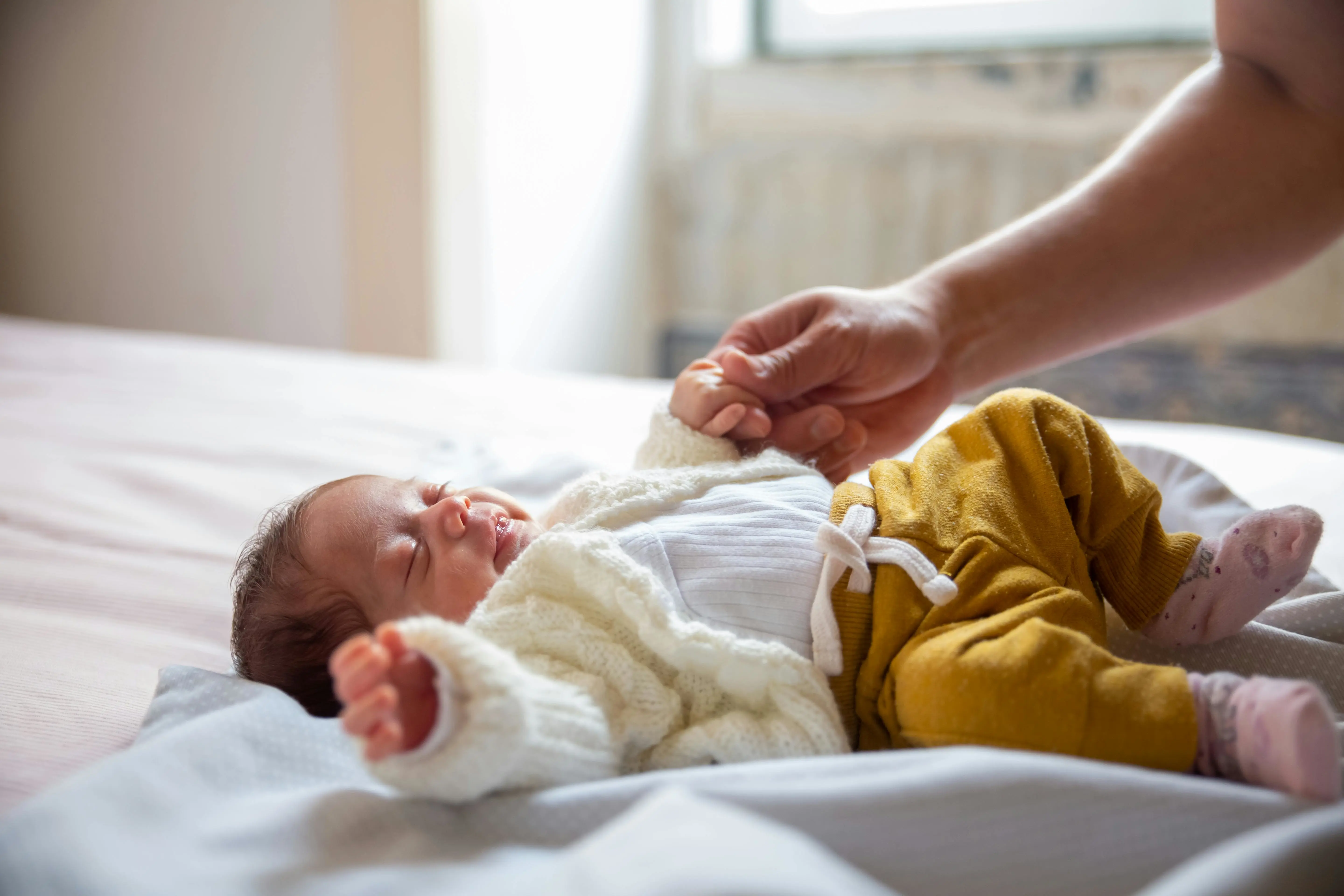 Een baby ligt op bed.