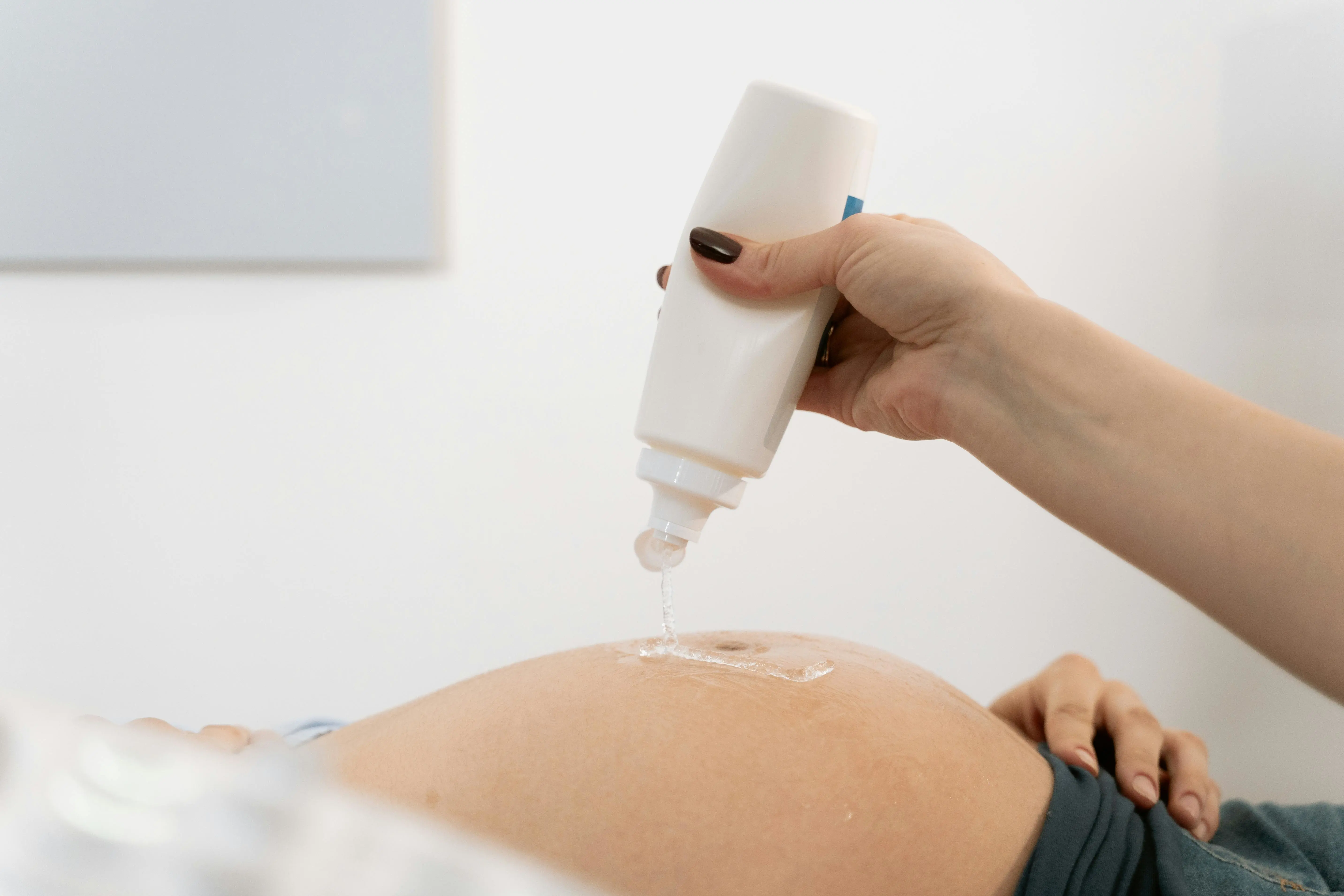 A midwife will do an ultrasound of a pregnant abdomen.