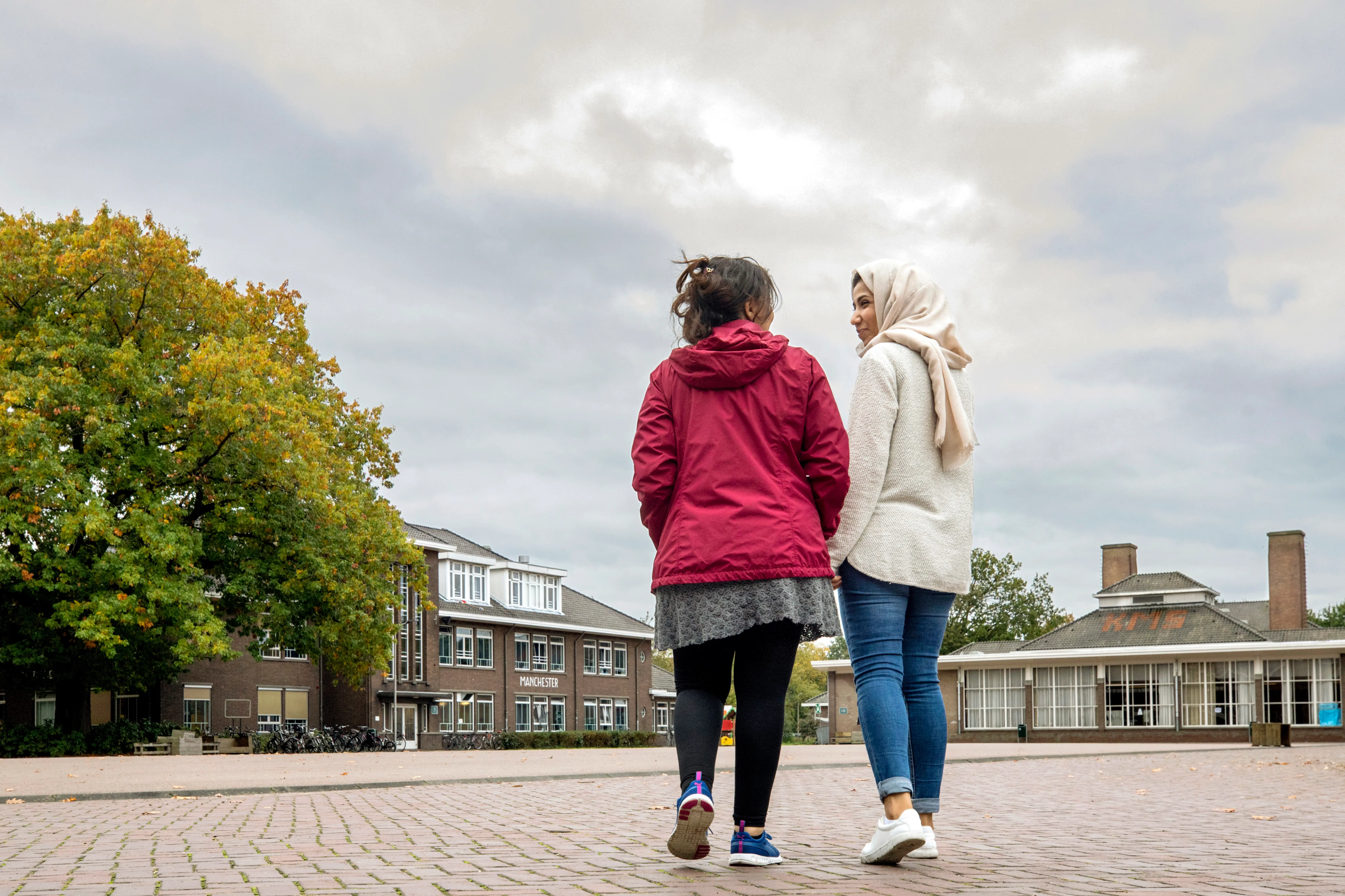 Two women walk on the square of the ASC in Weert and talk to each other.