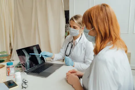 Twee artsen bekijken een röntgenfoto op een laptop