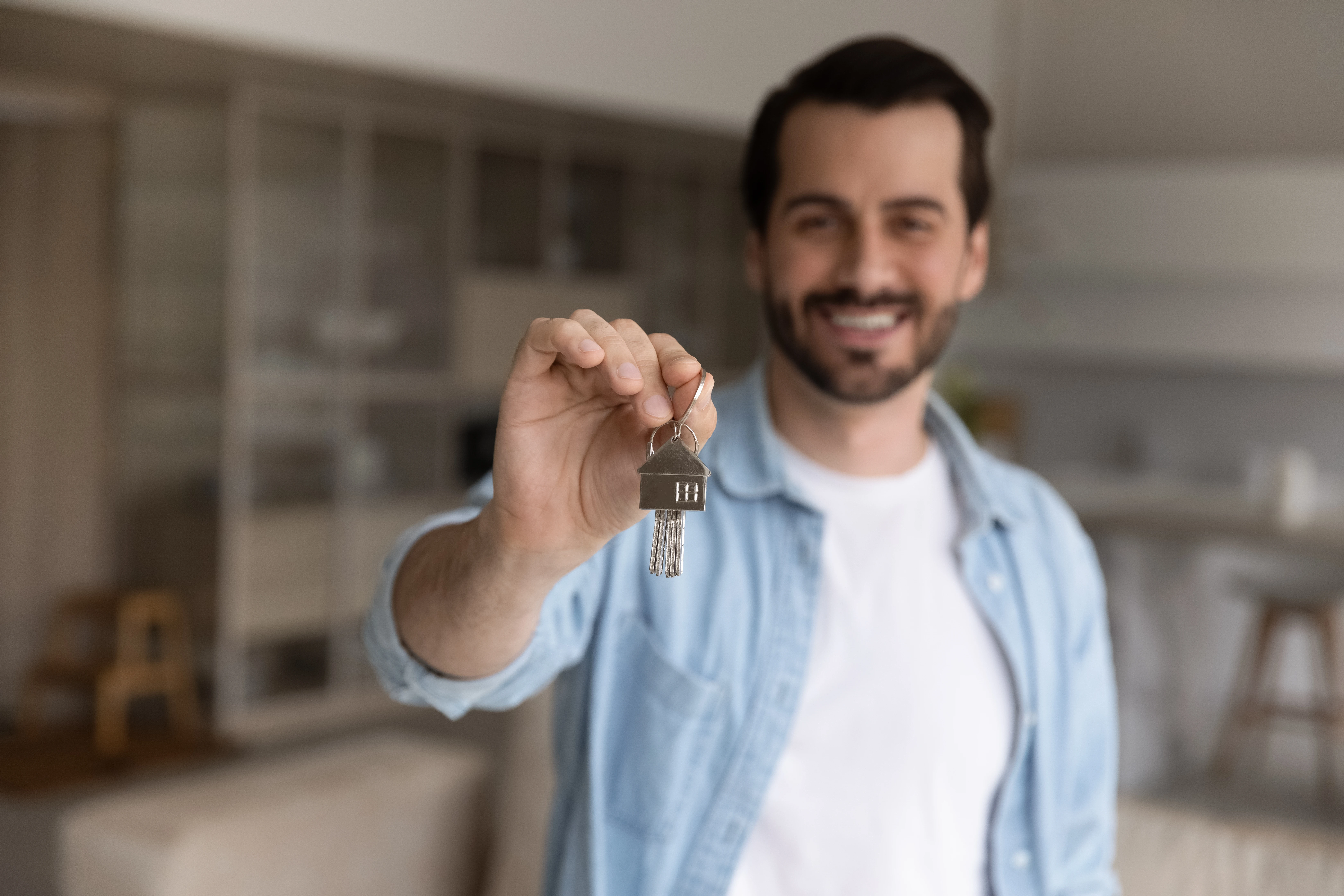 Un homme tient ses clés de maison en l'air.