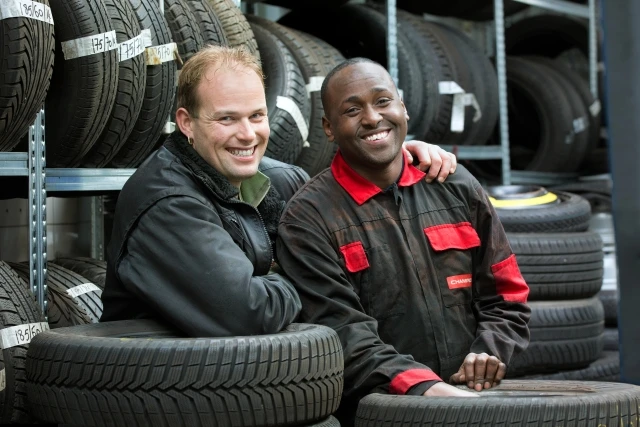 Car mechanic and colleague look smiling into the camera