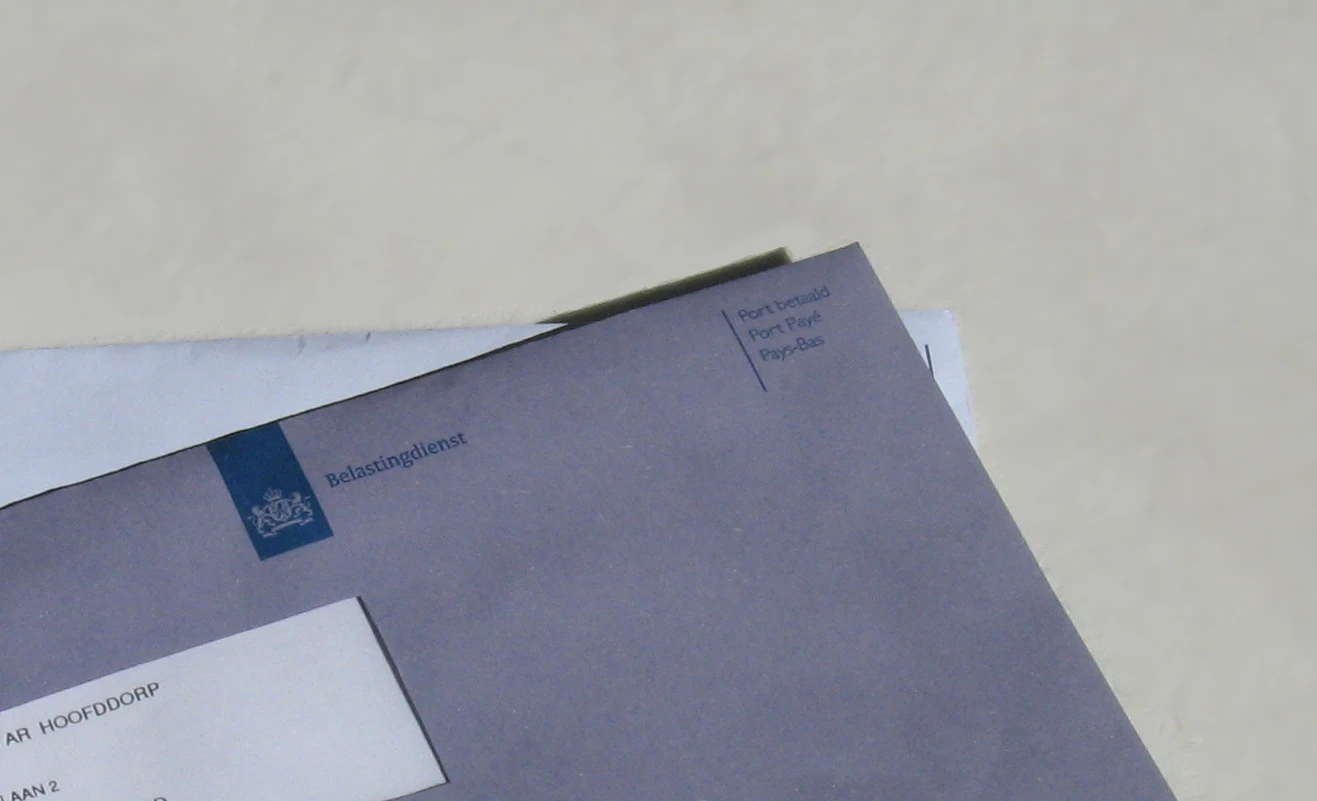 Een blauwe enveloppe van de belastdienst die op tafel ligt.