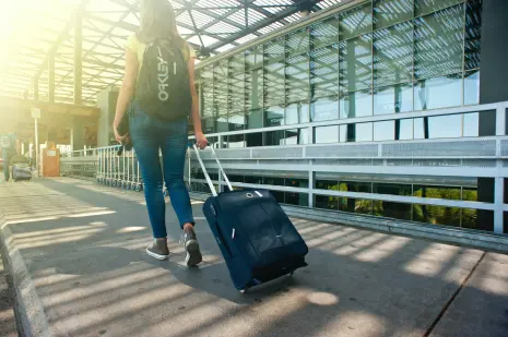 Vrouw loopt met bagage naar het vliegveld
