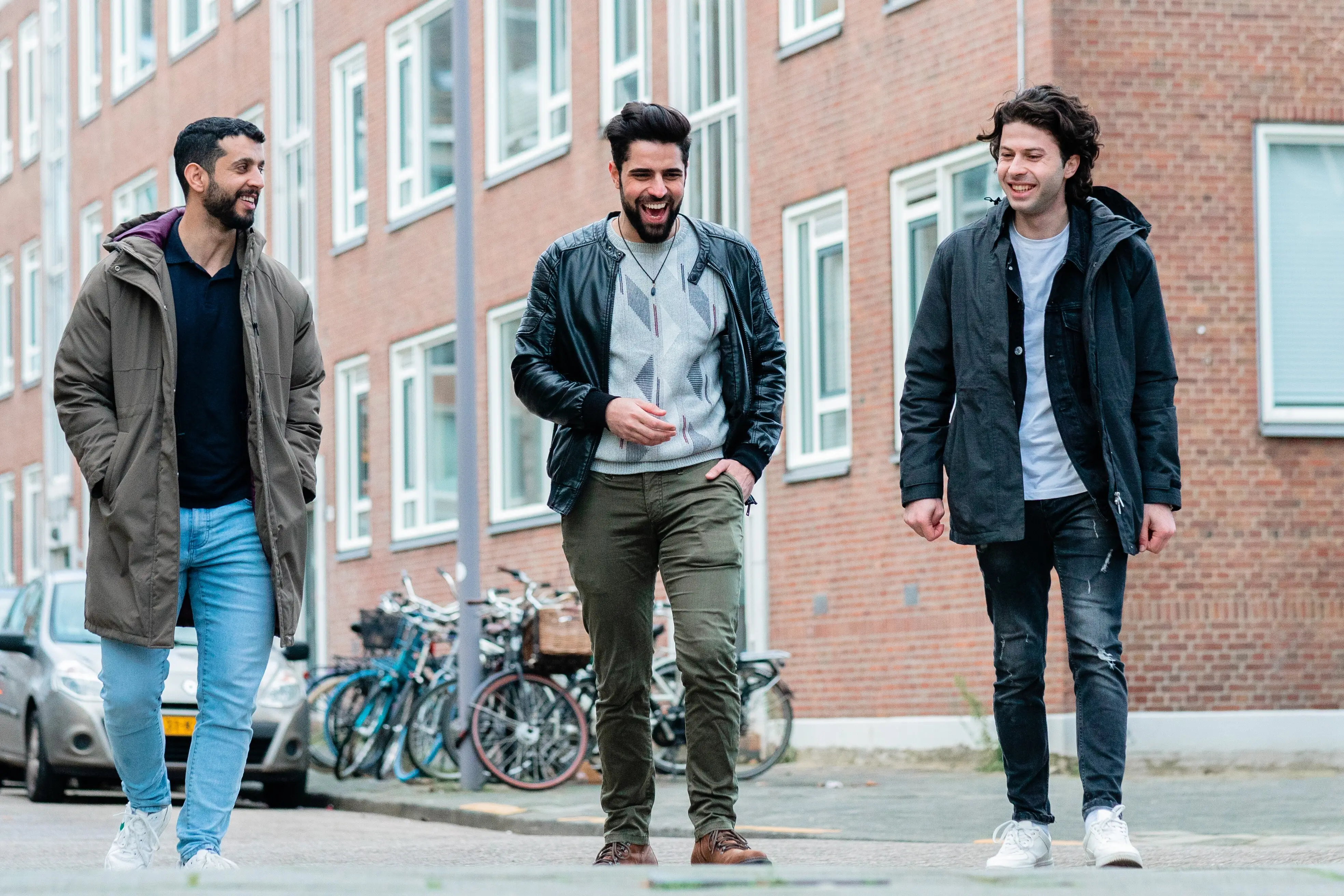 Twee Syrische jongens en een uit Jemen lopen pratend en lachend over straat in Rotterdam