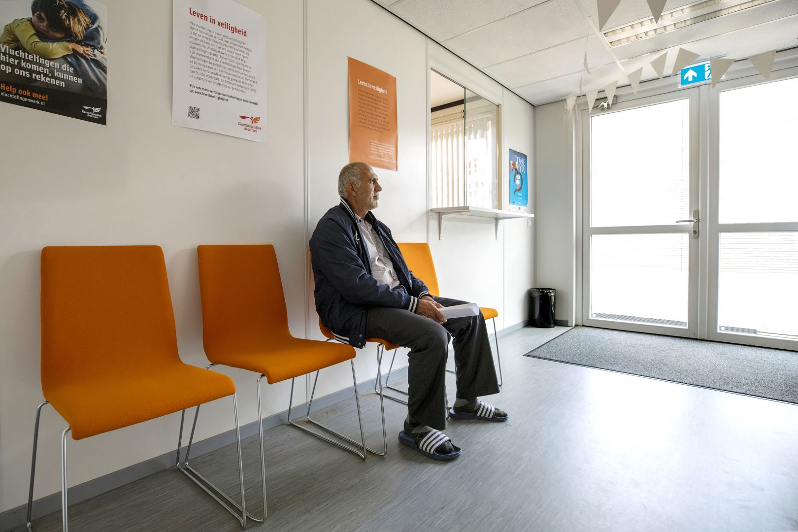 A man sits on a chair in a waiting room.