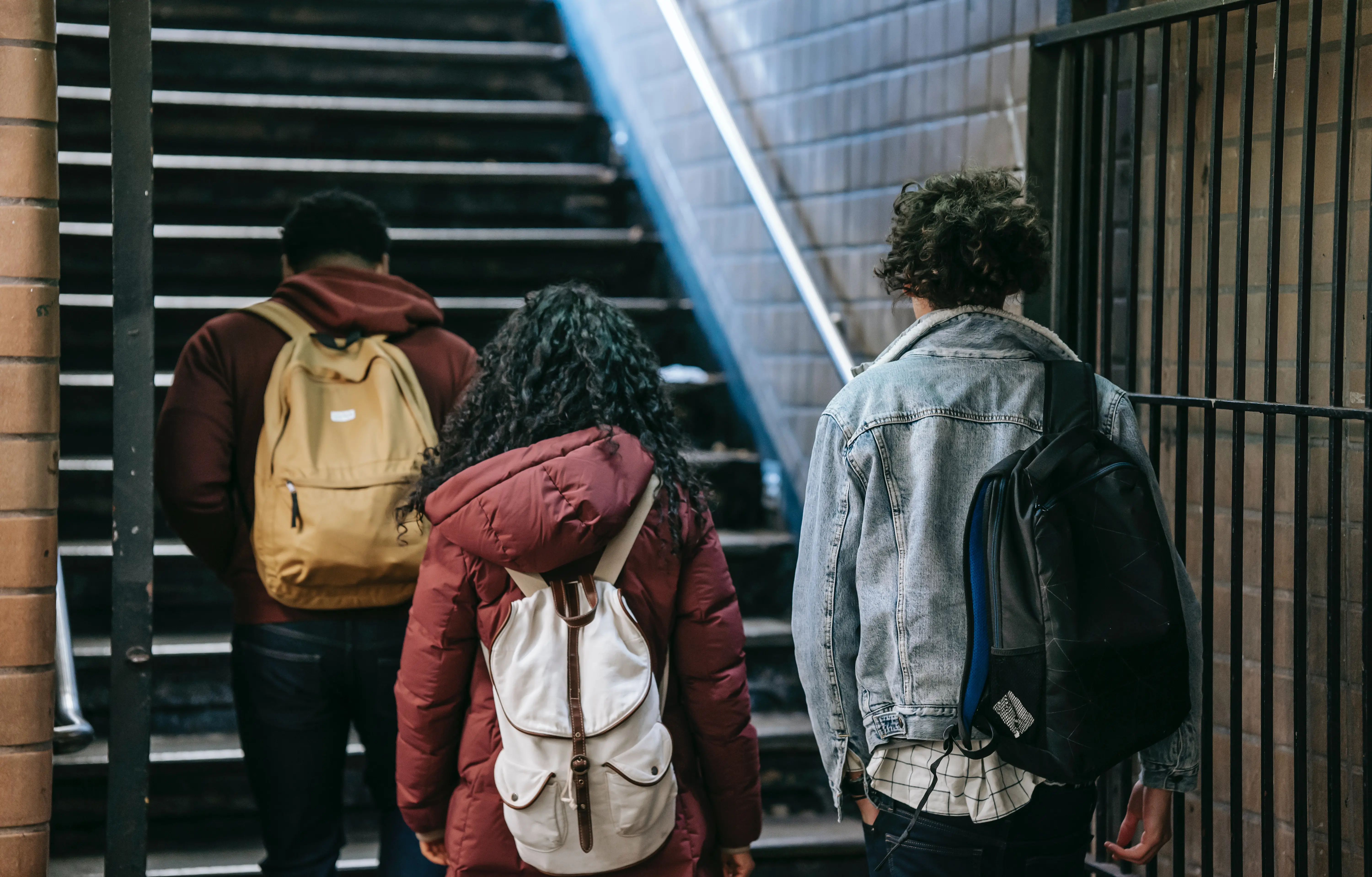 3 people with backpacks walk up stairs