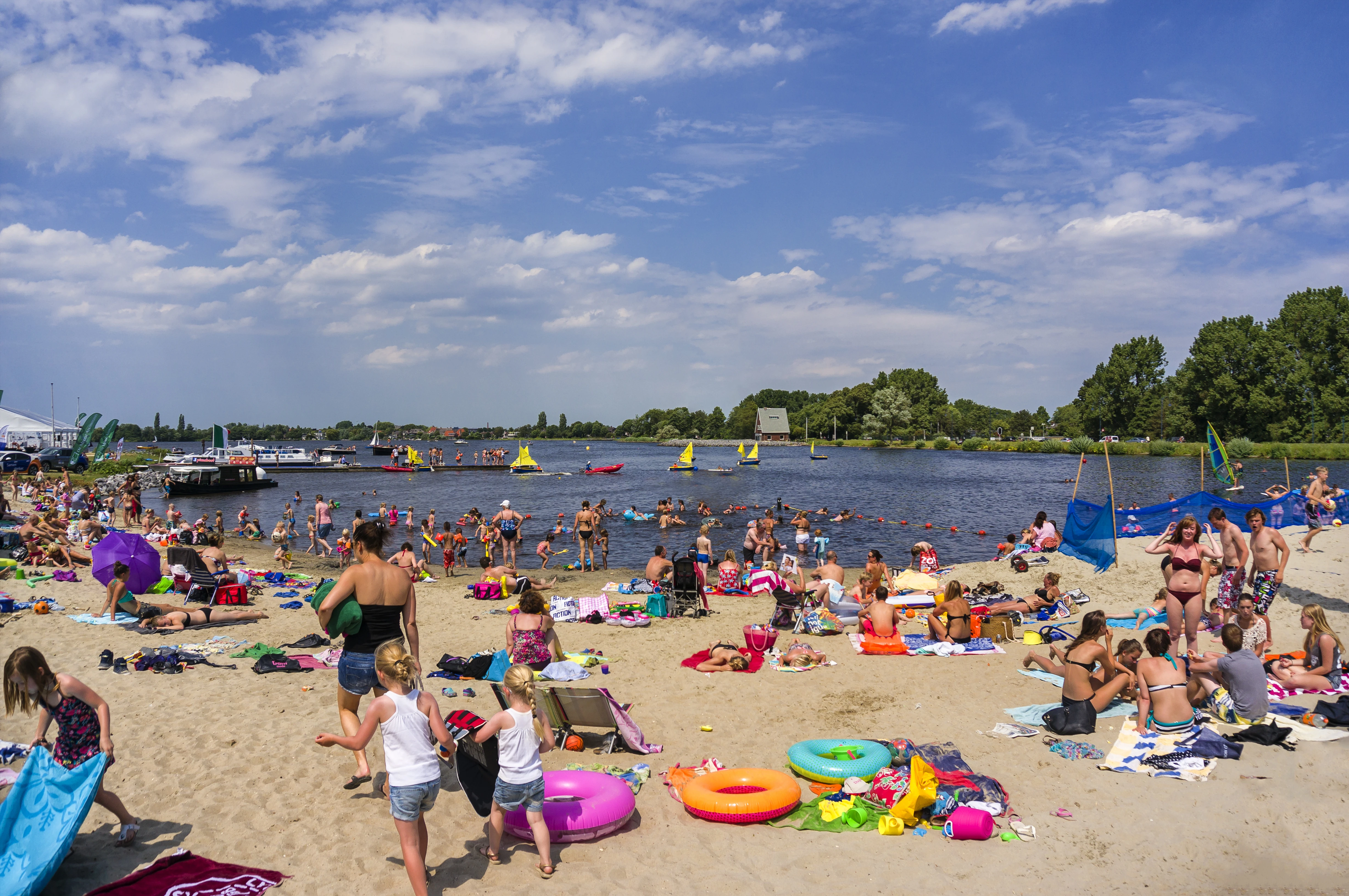 People sunbathe, play and swim on a sunny day in and near a lake in the Netherlands