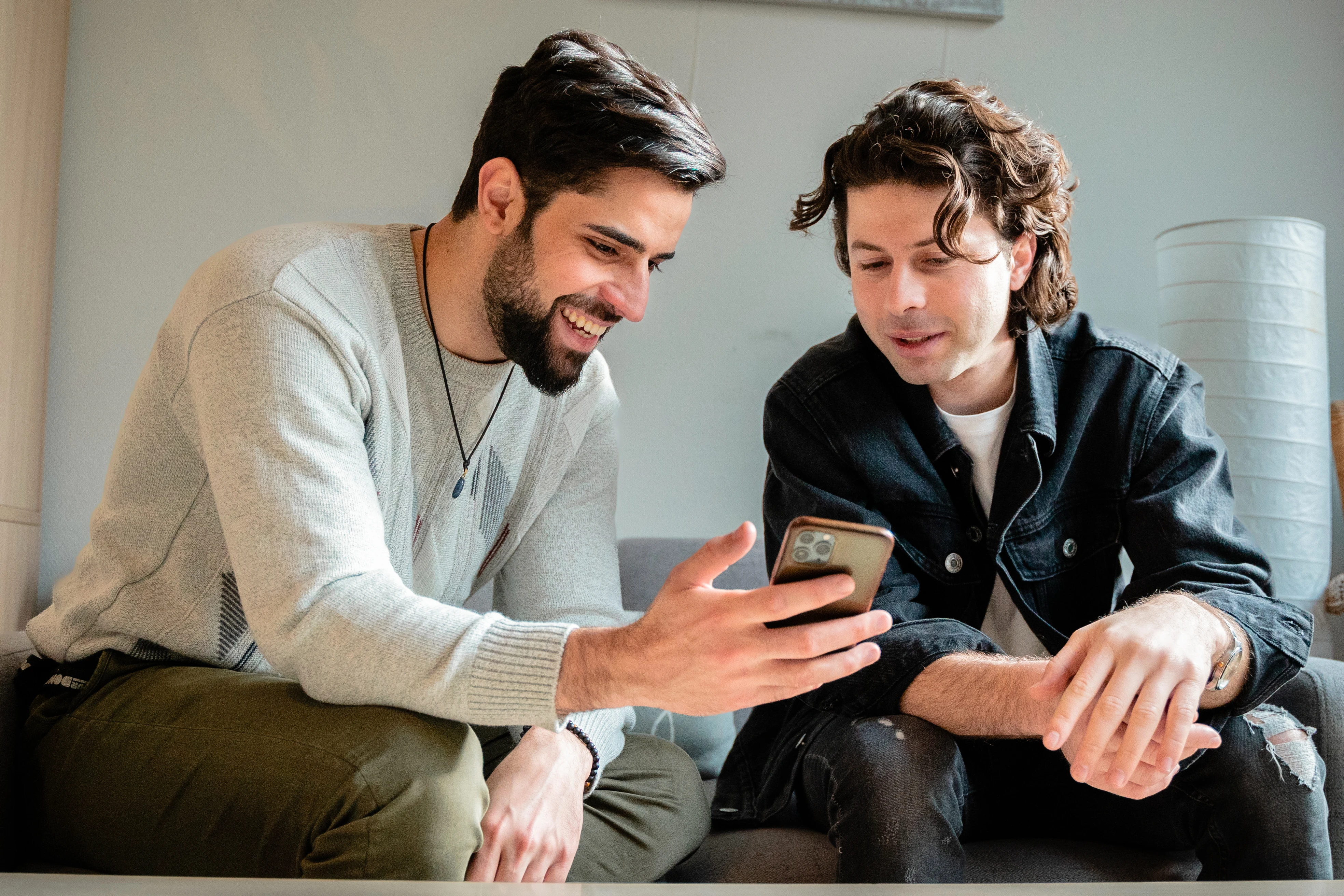 Twee mannen bekijken de website RefugeeHelp op hun telefoon. 