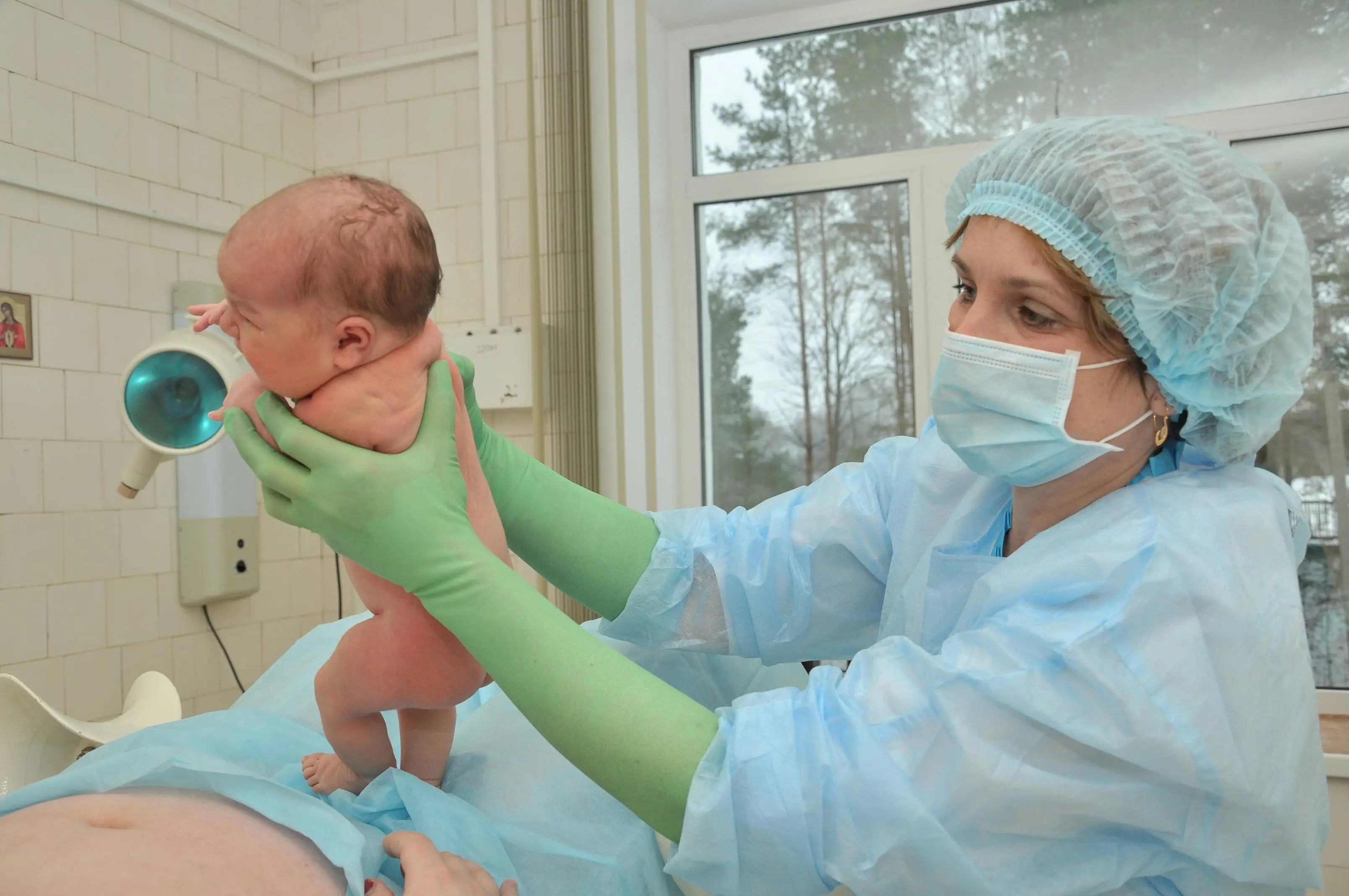 Een verloskundige laat de moeder haar pasgeboren kind zien.