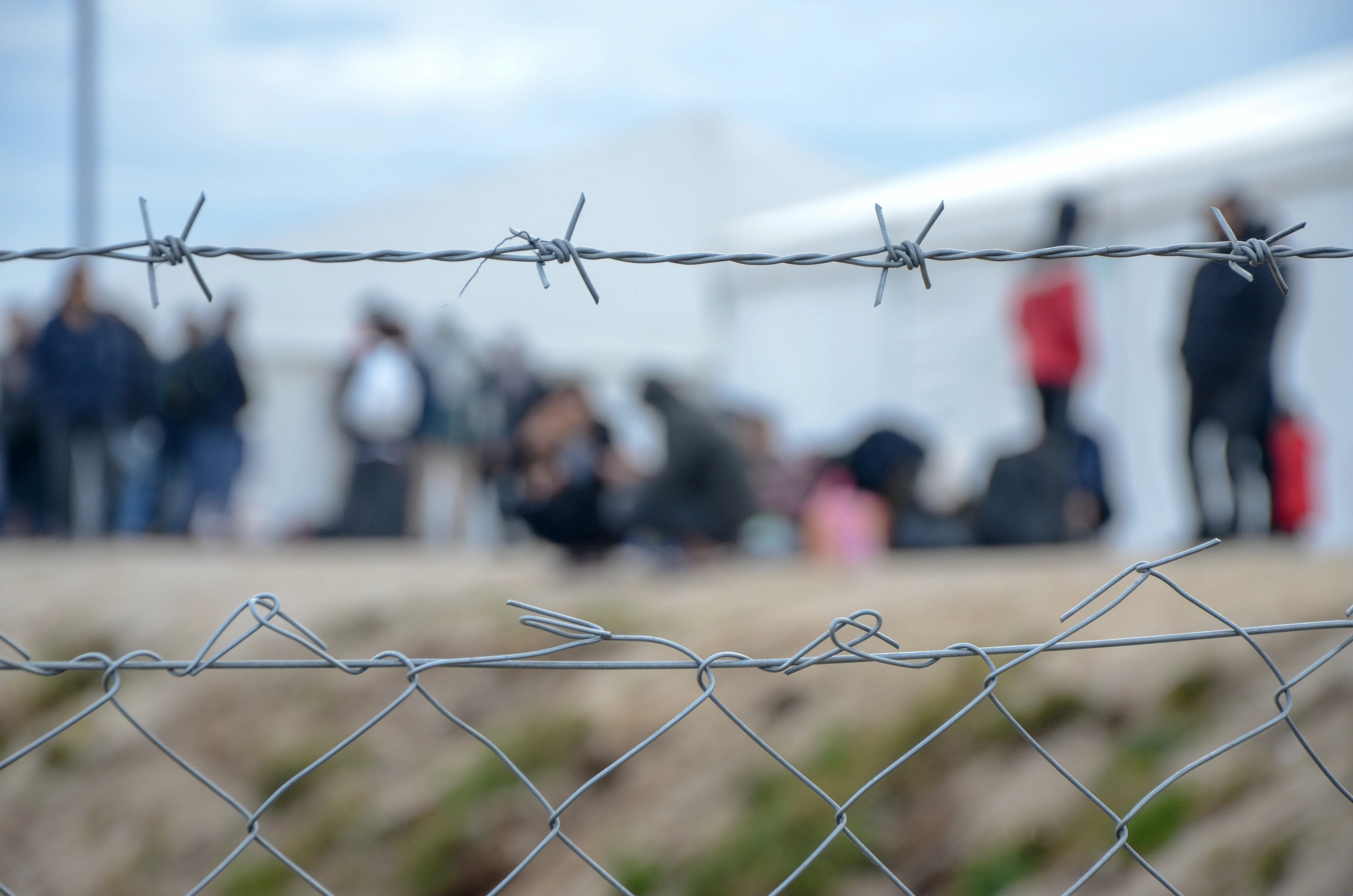 Refugees behind a barbed wire fence.