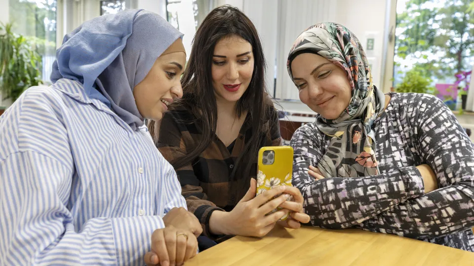 Drie vrouwen kijken naar hun smarthpone