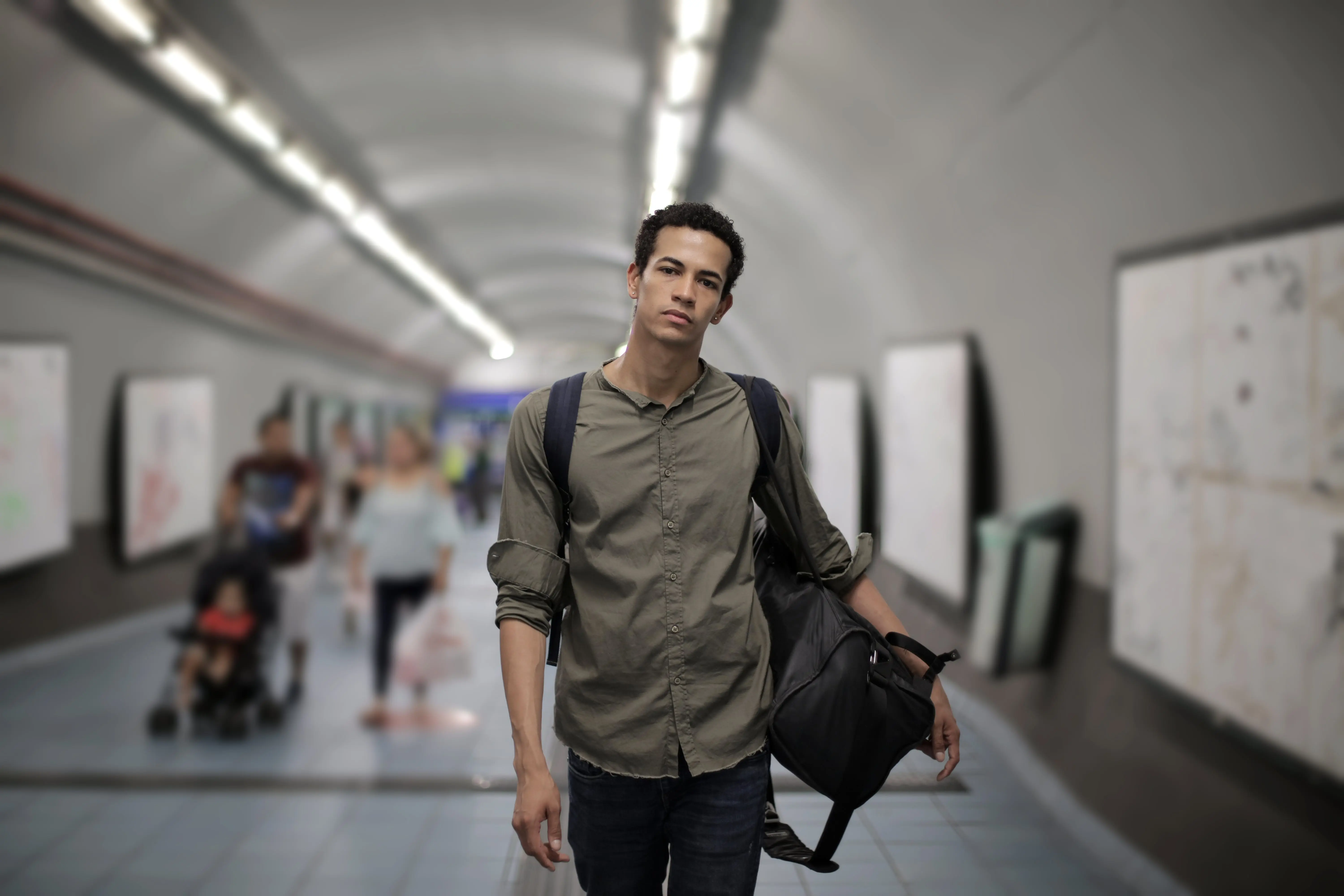 Young man with luggage over his shoulder walks through tunnel