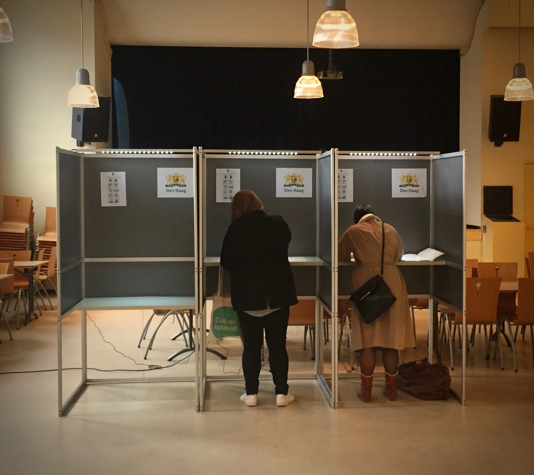 2 personen stemmen in een stemhokje tijdens de verkiezingen.