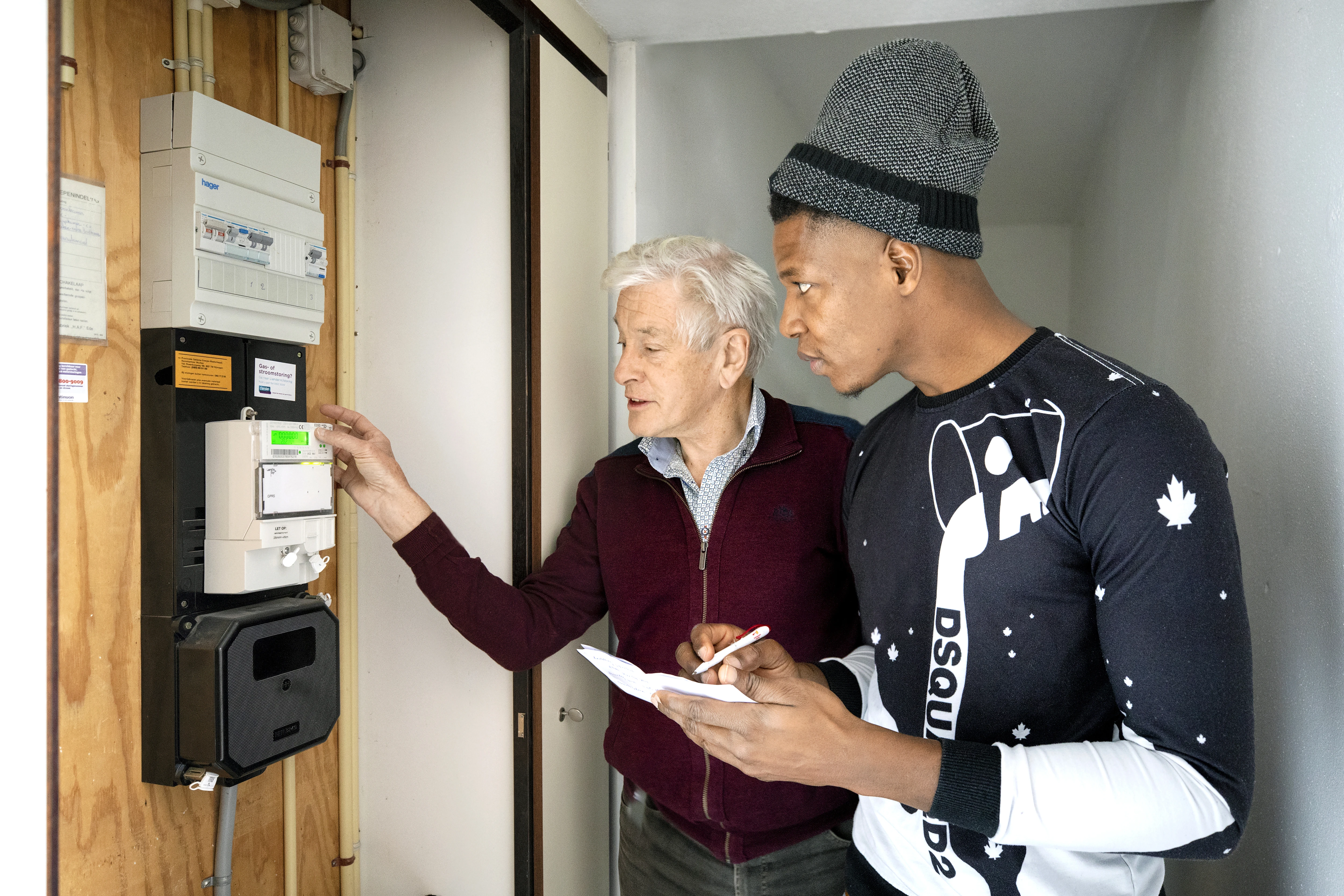 Two people stand at the meter box and write down meter readings