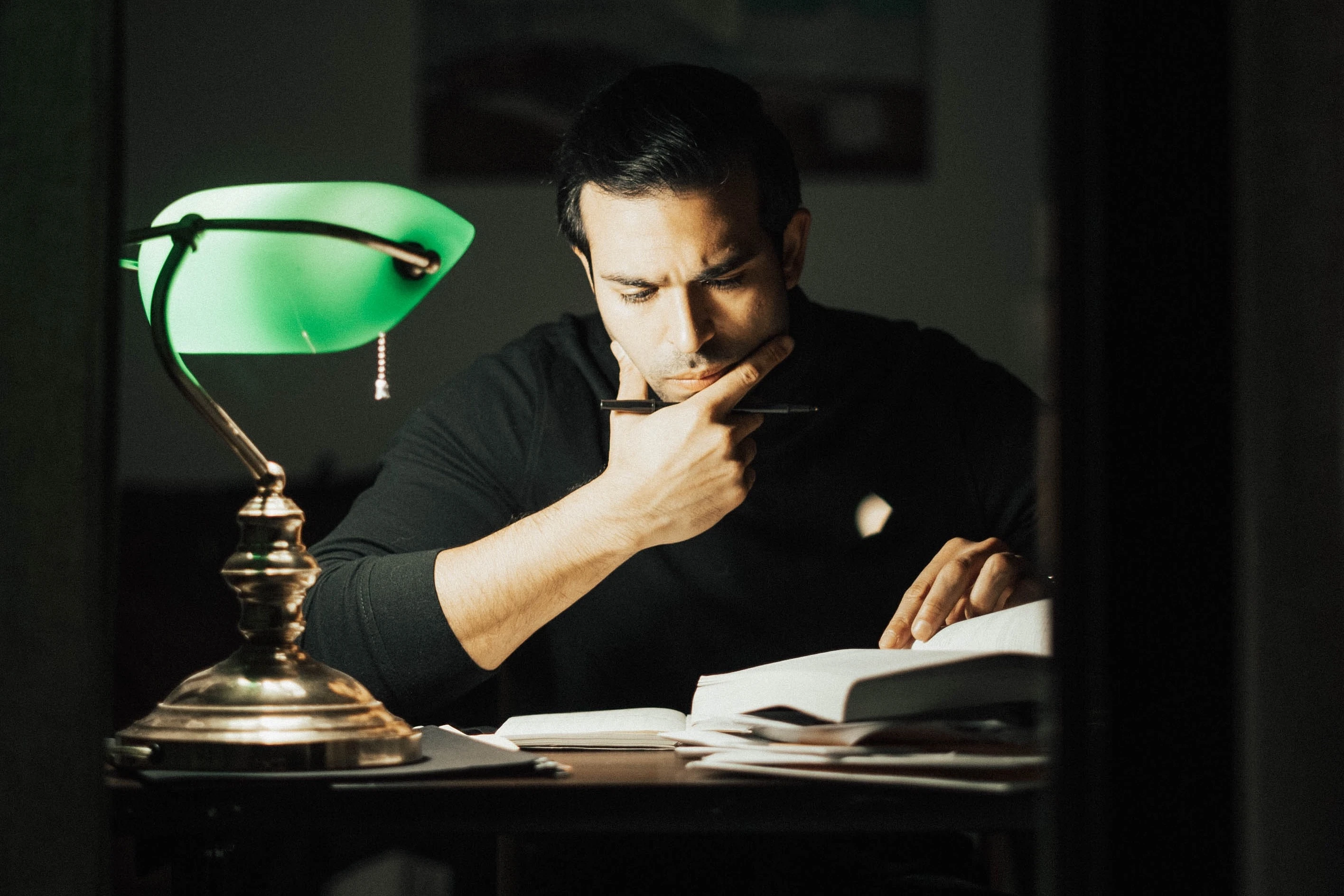 Een man leest een boek onder het licht van een leeslamp