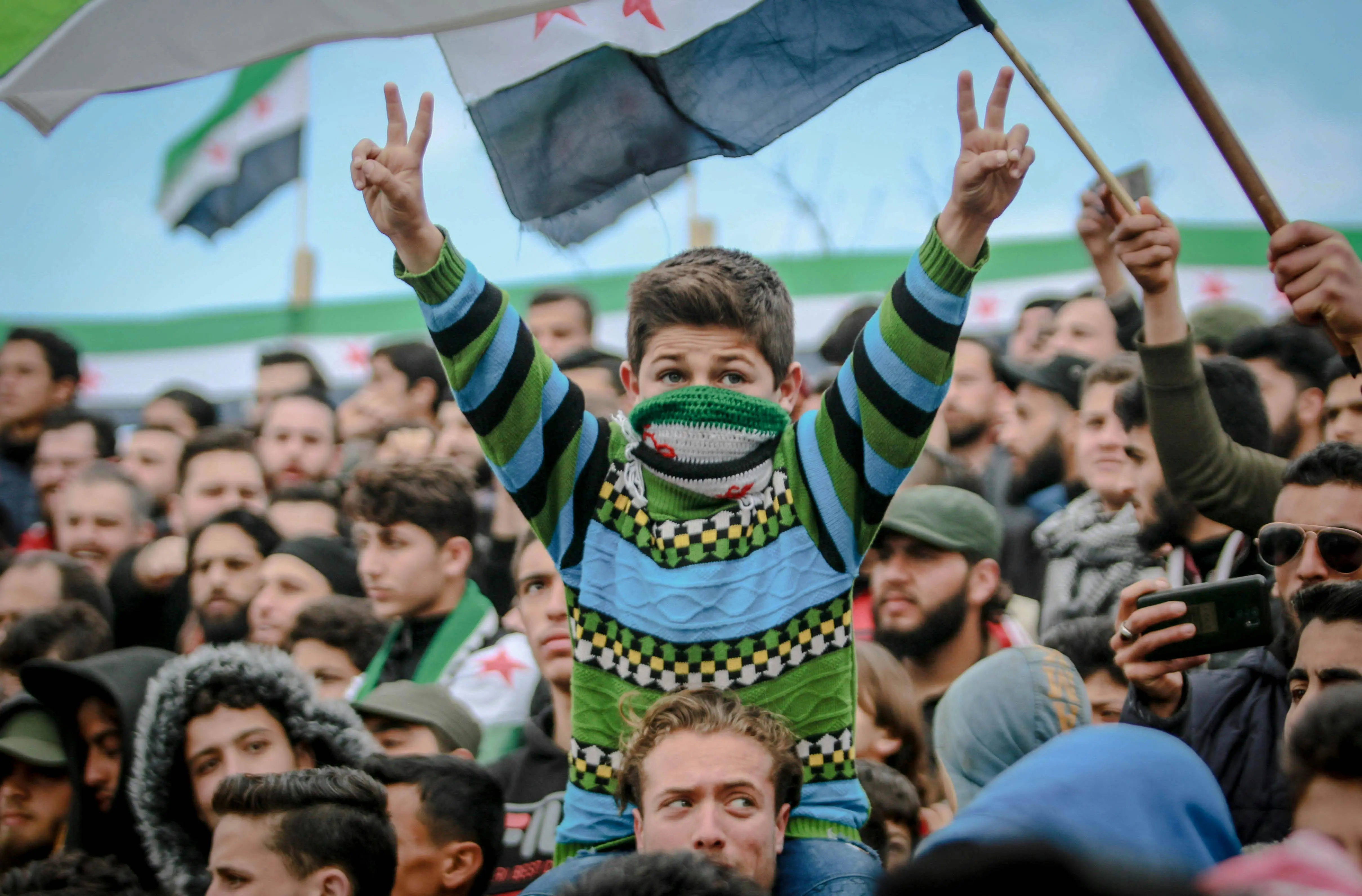 A Syrian boy makes a peace sign with his hands at a demonstration against Bashar al-Assad's regime.