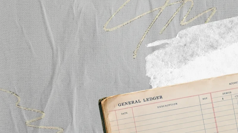 Vintage general ledger book with cream pages on gray fabric with gold embroidered text and white feather accent.