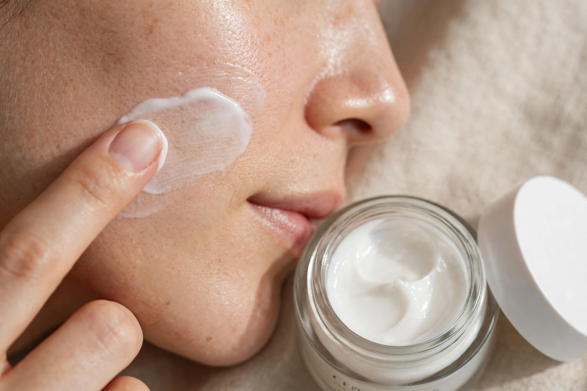 Woman with calm glowing skin applying moisturizer, concept for skin barrier repair routine