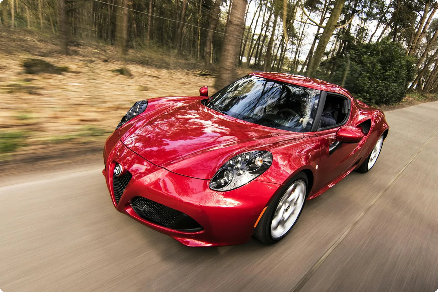 Raudonas sportinis automobilis lekia vingiuotu keliu – primenama, kad brangiai technikai gresia stichijos, subraižymai ar avarijos, todėl KASKO suteikia svarbią apsaugą.