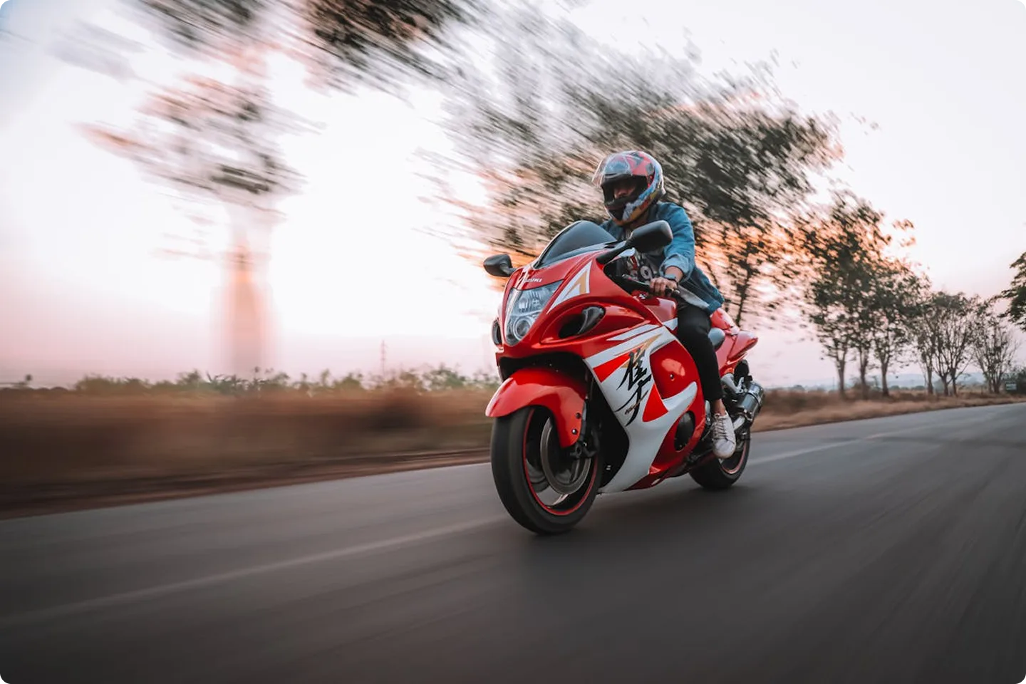 Raudonas sportinis motociklas važiuoja vingiuotu keliu – iliustracija pabrėžia, kad motociklininkams gresia didesnė rizika patirti nuostolius. KASKO draudimas suteikia finansinę apsaugą nuo vagysčių, avarijų ar gamtos stichijų.