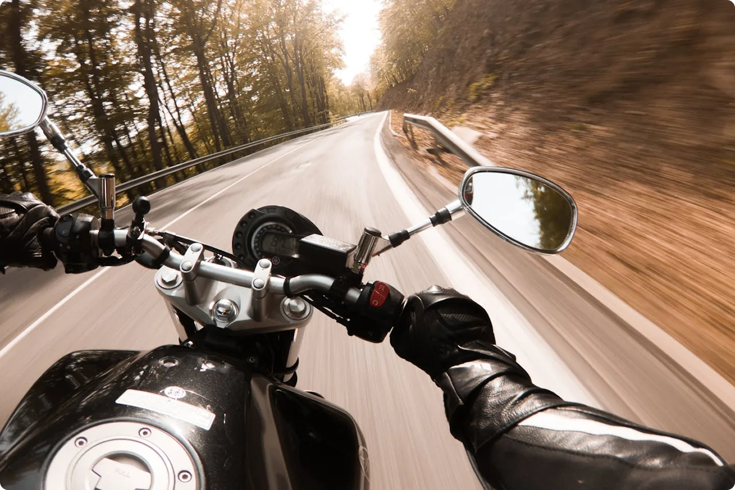 Vaizdas iš motociklininko perspektyvos važiuojant miško keliu perteikia laisvės pojūtį, tačiau primena ir rizikas. KASKO draudimas padeda jaustis saugiau kelionėse, apsaugodamas nuo netikėtų įvykių ir brangių remontų.