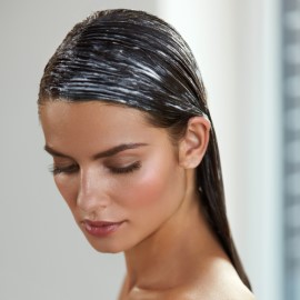 Mujer con cabello húmedo y con acondicionador para hidratarlo y repararlo