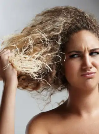 Mujer mostrando su cabello rizado deshidratado con puntas muy secas