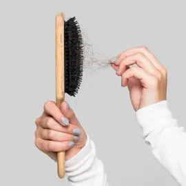 Mujer quitando cabello caído de las cerdas de su cepillo