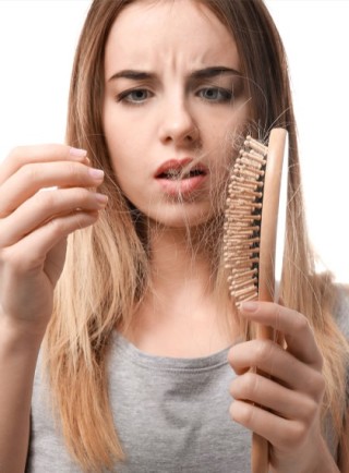 Mujer preocupada por los cabellos en su cepillo