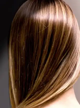Mujer de espaldas con su cabello quebradizo peinado sobre un hombro