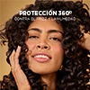 Mujer con cabello crespo, protección 360 contra el frizz y la humedad