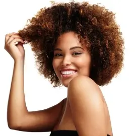 Mujer luciendo su cabello afro mientras estira un mechón de rizos