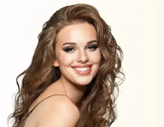 Mujer pelirroja sonriendo mientras luce su cabello sedoso y radiante