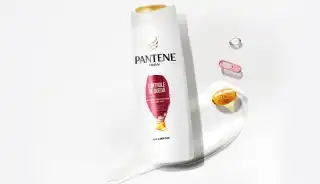 Botella de Shampoo Control Caída de Pantene junto a Cápsulas de ingredientes