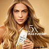 Mujer rubia con la botella de shampoo Molecular Bond Repair repara la fibra capilar 5X más fuerza