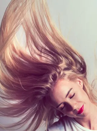 Mujer con cabello tinturado moviendo la cabeza para lucir su melena