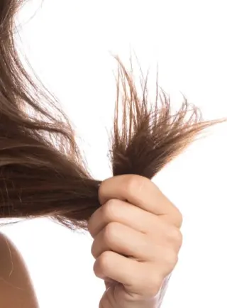 Mujer sosteniendo su cabello, mostrando sus puntas abiertas