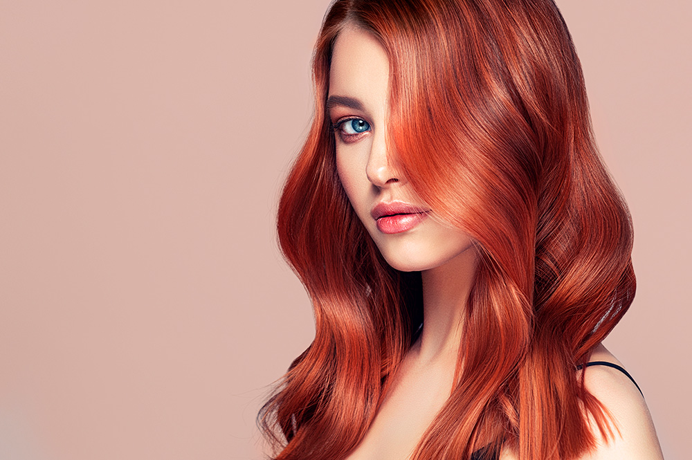 Mujer con pelo rojo con color con brillo y vitalidad por usar los productos Pantene.