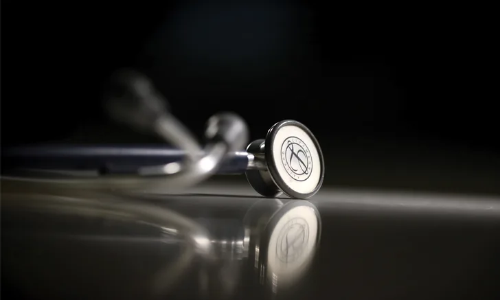 A stethoscope lying on a dark, reflective surface.