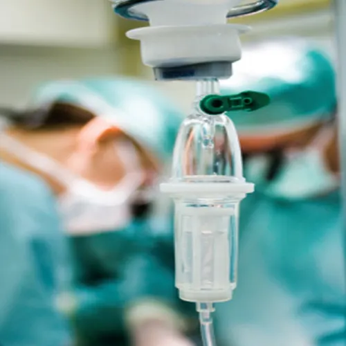 Close-up of drip chamber of an IV drip set inserted into fluid bag.