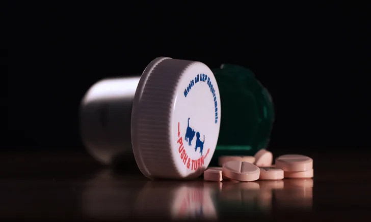 A pill bottle lying on its side with pills spilling out from it.
